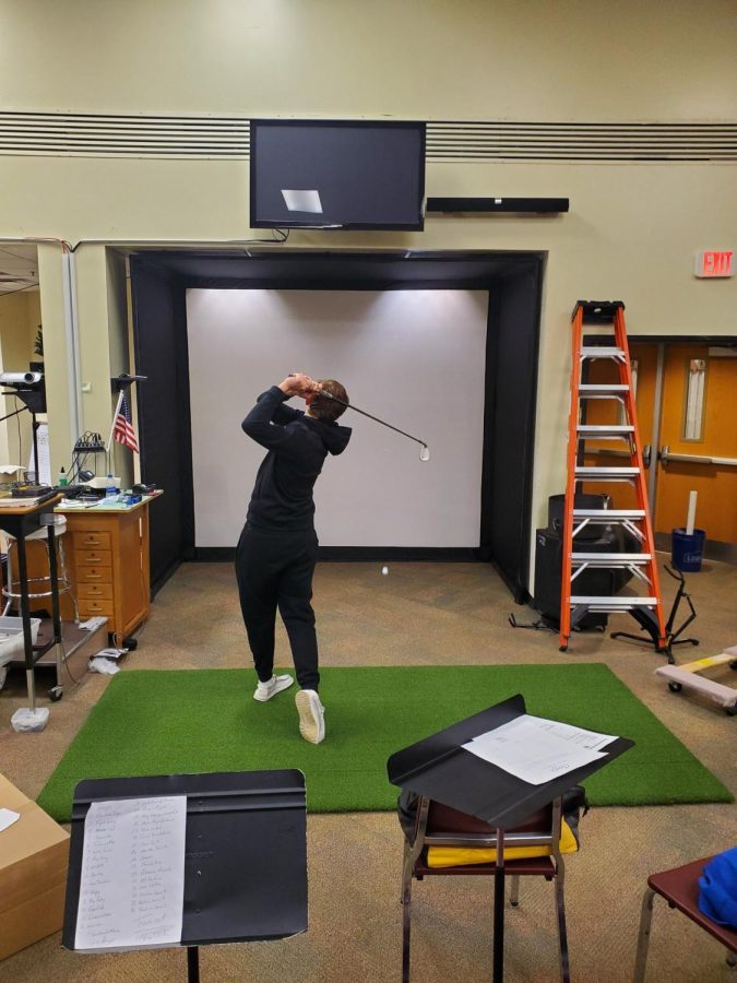 Junior Ian Hollander using the new golf simulator in the band room.