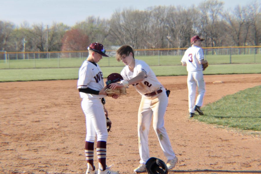 Freshman Lucas Stahlschmidt giving sophomore Noah Gramling a hat fot the next inning.